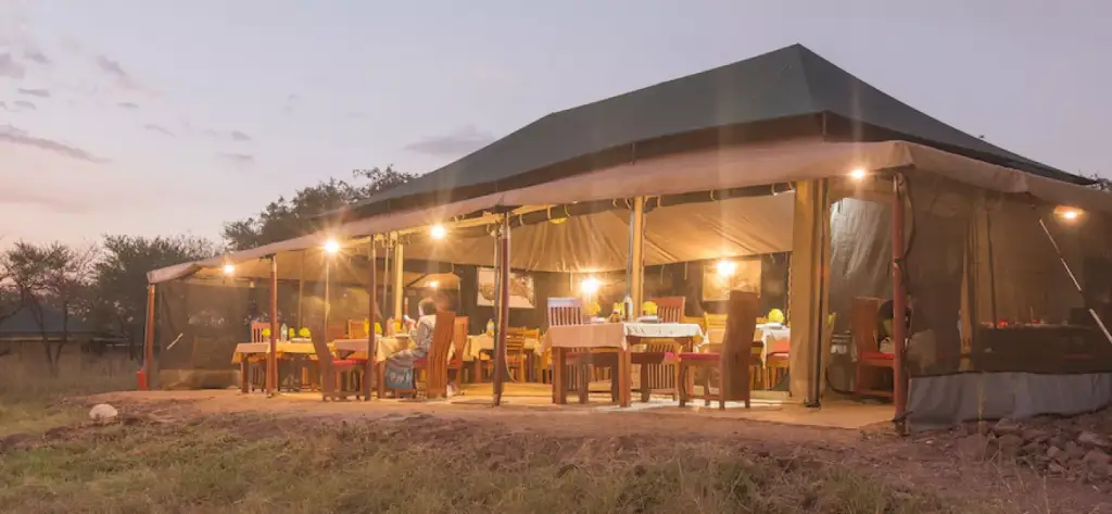 A safari tented camp lit up at dusk